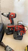 Photo showing Black and Decker 12V cordless drill, two 12V battery packs, and a charger on a table.