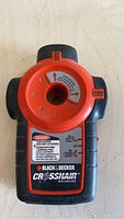 Photo of a Black & Decker Crosshair Auto Laser Stud Finder showing front view with laser emitter and warning labels visible.