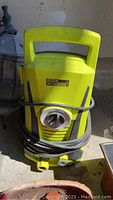 Photo of bright yellow Power It VAS Y outdoor pressure washer with hose coiled around front.