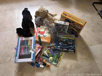 Overview of lot showing stuffed animals, books, art supplies, games, and toys arranged on floor.