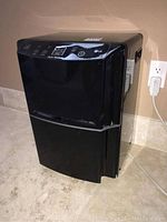 Front and side view of black LG dehumidifier on tiled floor