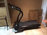 Full view front left of treadmill unfolded showing black frame, deck and handles