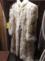 Full front view of the long fur coat hanging in closet