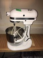 Front view of white stand mixer with bowl and attachments inside