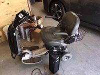 Full view of AutoGo Vision mobility scooter with seat, foot platforms and spare battery visible on floor