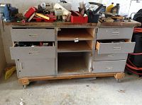 Front view of metal tool cabinet with several drawers open showing contents and wear.