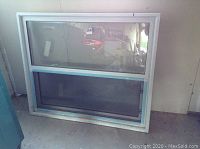 Full view of the new window leaning against the wall showing clear glass pane and screen panel below.