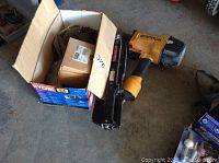 Pneumatic nail gun beside two boxes of fasteners, showing overall lot contents