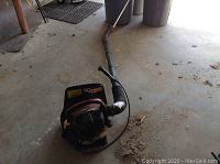 Full view of the Homelite backpack blower with long flexible tube on floor.