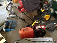 Overall view of push weed whacker with accessories in garage setting