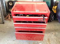 Full front view of the red Waterloo tool chest with drawers partially open showing tools inside and visible wear.
