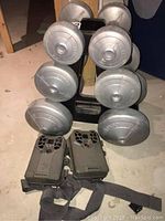 Photo of two Stealth Cam trail cameras in front of a dumbbell tree with six dumbbells.