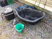Full lot showing black molded plastic pond liner, two water pumps, green utility bucket, and a box.