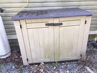Front view of closed two-door resin storage shed against exterior siding
