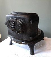 Side view of cast iron bot belly stove base with visible front latch and legs
