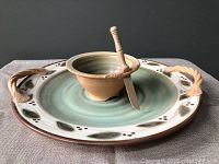 Front view of the pottery platter with dip bowl centered and wooden spreader resting on bowl