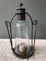 Metal and glass hurricane lantern assembled with candle inside.