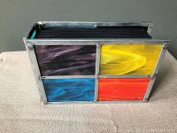 Photo album on side showing marbled stained glass panels in purple, yellow, blue, and red colors with metal framing and screws