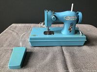 Front view of blue vintage Holly Hobbie children's sewing machine toy showing character decal and foot pedal.