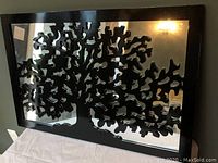Front view of rectangular wall mirror showing black tree silhouette design overlay on clear mirror surface with glossy black frame.