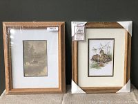 Two wooden picture frames side by side, one with a nature scene and the other with a lynx family art print. Both are partially wrapped in protective plastic and corner protectors.