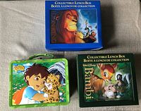 Photo showing three collectible lunch boxes: The Lion King, Bambi, and Go Diego Go.
