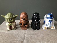 Front view of four Star Wars handheld flashlights lined up showing Yoda, Chewbacca, Darth Vader, and R2-D2 figure designs.