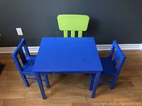 Blue children's play table with two matching blue chairs and a green chair shown from above and front angle.