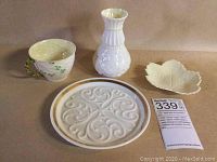 Four porcelain items including Belleek teacup, bud vase, leaf plate, and Lenox decorative plate all arranged together
