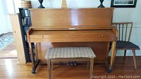 Front view of the Baldwin Hamilton upright piano with closed keyboard cover and bench in front