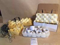 Photo showing 7 white ceramic cups placed in plastic container, with two foam holders containing glass measurement devices attached to black Amphenol RFx cables.