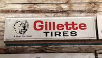 Full front view of rectangular metal sign showing brand name Gillette Tires, bear logo, and slogan