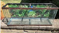 Large bowfront aquarium with wooden trim shown from front and side, in outdoor setting