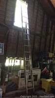 Tall single aluminum ladder leaning against wall, showing ladder height and overall condition.