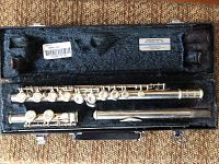 Flute disassembled in case showing headjoint, body, footjoint with silver finish and keys.