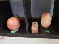 Display of spherical salt lamp on left, stone-shaped salt lamp on right, and rectangular two-spot tea light holder in middle on shelving cubby