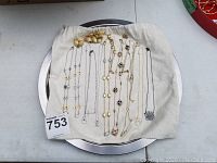 Photo showing full assortment of costume jewelry including bracelets with large gold beads and various long necklaces with mixed metal pendants and beads.