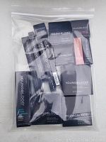 Photo shows a plastic zip bag containing multiple mineral cosmetics boxes and tubes arranged inside, primarily black packaging with Youngblood branding.