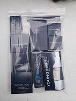 Top view of multiple boxed Youngblood cosmetics, including foundations and blushes, arranged in sealed plastic bag.