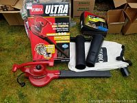 Full view of Toro Ultra Electric Blower Vac with original box, collection bag, vacuum tube, and blower nozzle laid out on grass.