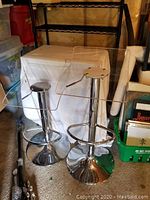 Two clear resin adjustable height swivel bar stools and small two-tier rolling round table