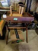 Wooden desk organizer tray on foldable stand with small round wooden footstool placed upside down on the tray