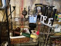 Overview of wire rack shelf holding various decorative items including carved wooden hummingbirds, metal candle holders, 'LOVE' letters, small clock and others