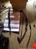 Two recurve bows laid on top of a paper target sheet on carpet