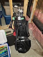 Full view of the TaylorMade golf bag containing the set of golf clubs in an unfinished basement environment.