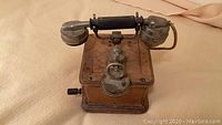 Overall view of the antique French crank telephone showing wooden box base, metal handset, and crank.