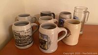 Group of 7 German beer steins in ceramic and glass placed on a wooden surface corner shelf.