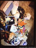 Photo showing large collection of sewing and craft items scattered on floor including thread spools, ribbons, fabric, and boxes