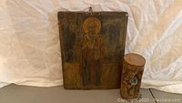 Front view of Russian icon and small carved bird figurine on log base side-by-side
