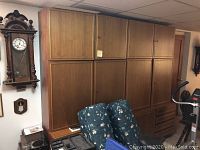 Photo of large wooden German wall unit with three upper doors and lower section with drawers and doors.